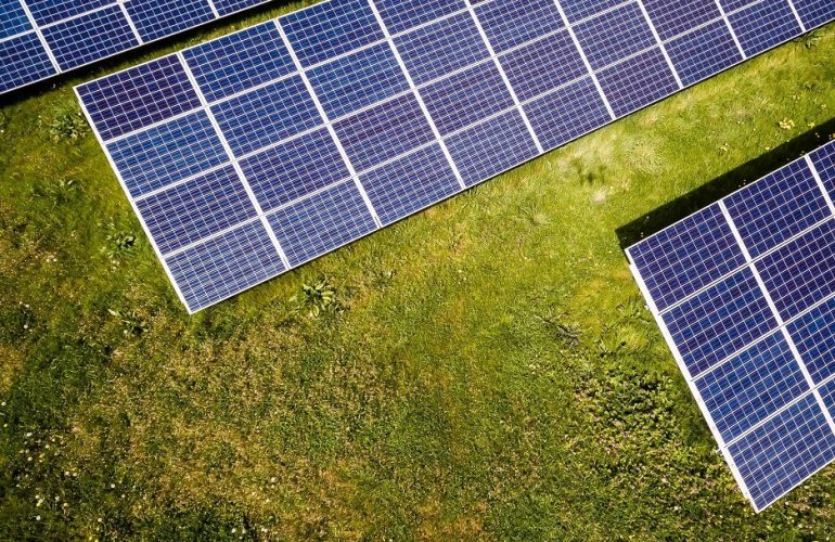 Pormenor de painéis solares fotovoltaicos sobre a relva, contemplados no financiamento do Banco Europeu de Investimento
