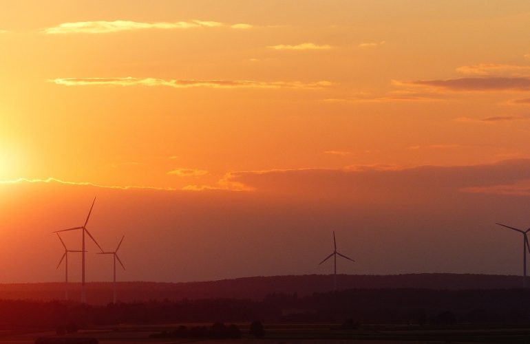 Pôr do sol junto a turbinas eólicas, cuja produção contribuiu para 61% de renováveis em Portugal até junho