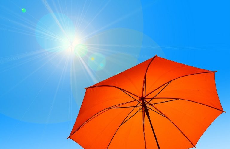 Guarda-sol laranja sob a luz do sol num céu azul