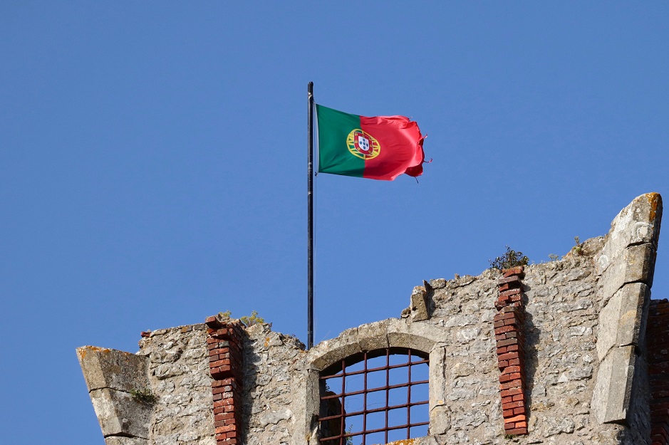 Ruína em tijolo com a bandeira portuguesa hasteada, um símbolo do turismo nacional